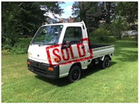 a small white truck parked in a grassy area