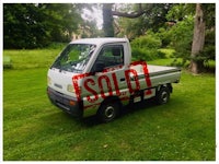 a small white truck parked in a grassy area