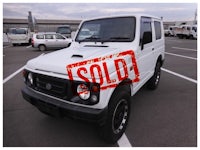 a white suzuki samurai parked in a parking lot