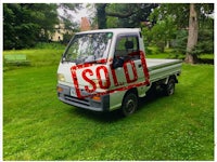 a small white truck parked in a grassy area