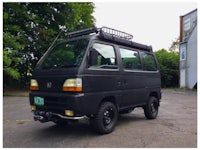 a black van is driving down a rocky trail in the woods