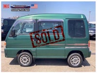 a green suzuki van parked in a parking lot