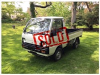 a white truck with a sold sign in the grass